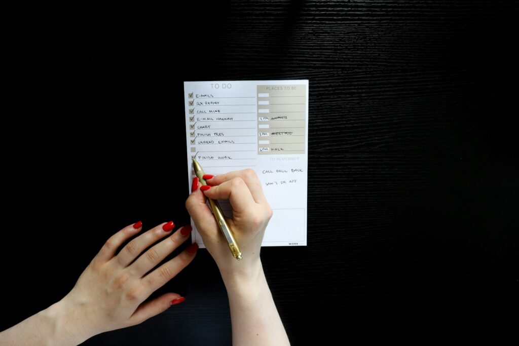 person holding pen writing on white paper
