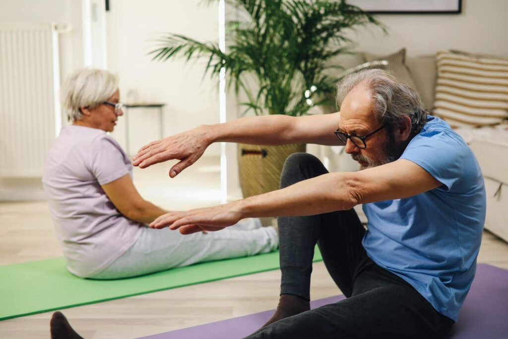 Elderly couple practicing yoga indoors with focus on wellness and fitness.