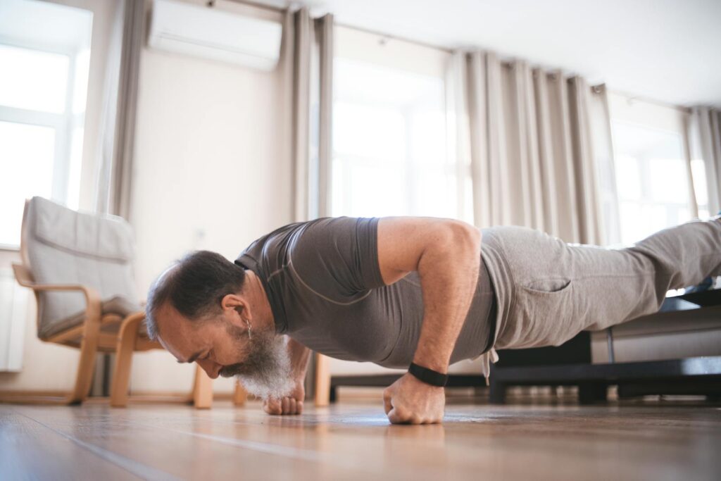 An elderly man performs push-ups in a bright indoor setting, showcasing strength and fitness.