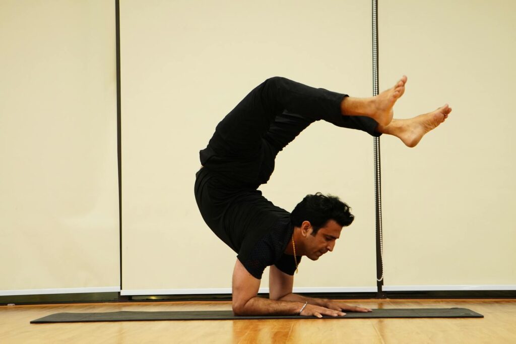 A man demonstrates impressive flexibility and skill performing a handstand on a mat indoors, showcasing balance and athleticism.
