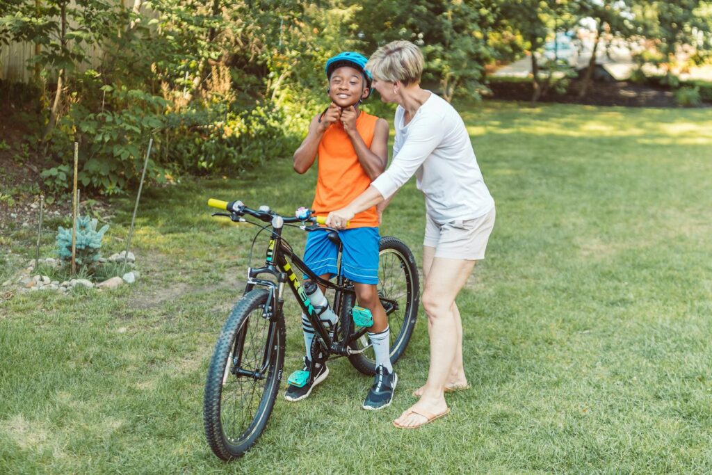 Mother guiding her son on a bike in a green park, enjoying a sunny day.