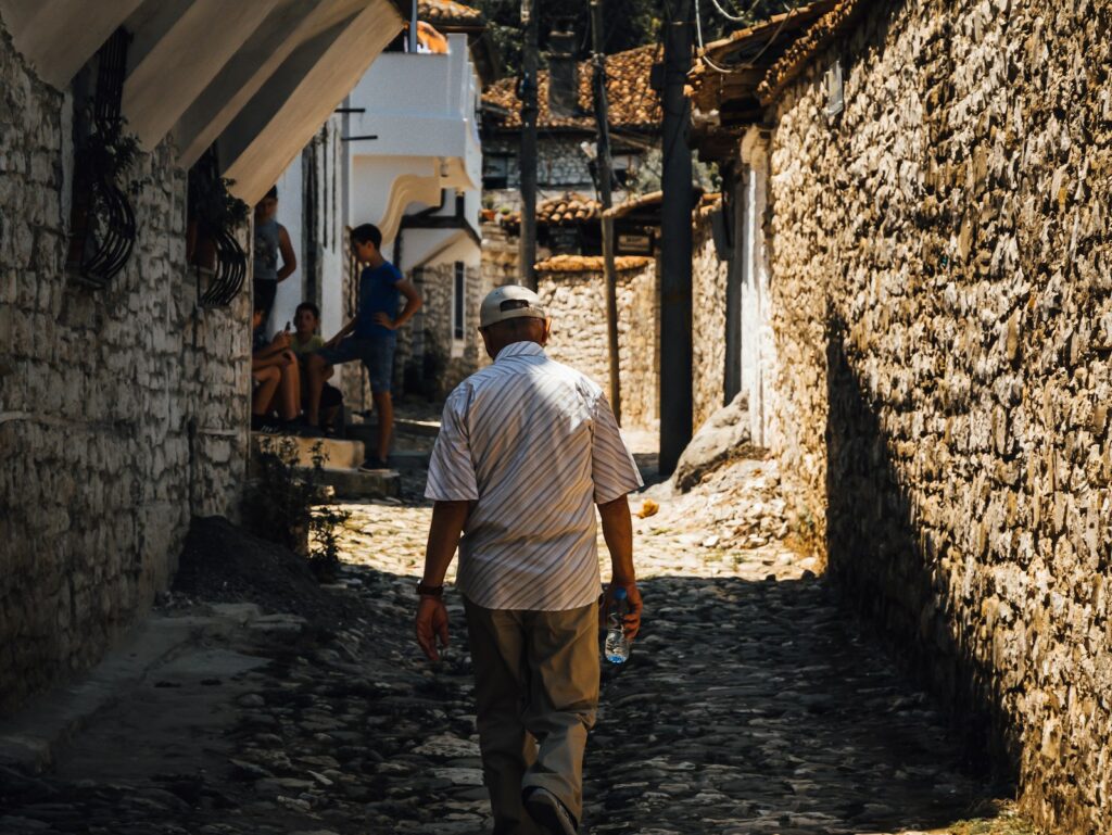 man in white button up shirt and brown pants standing near brown brick wall during daytime